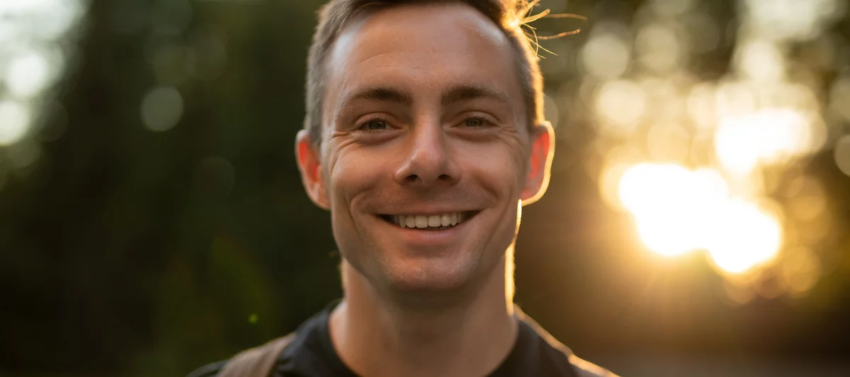 Kolorowe zdjęcie przedstawiające uśmiechniętego młodego mężczyznę patrzącego w kierunku aparatu